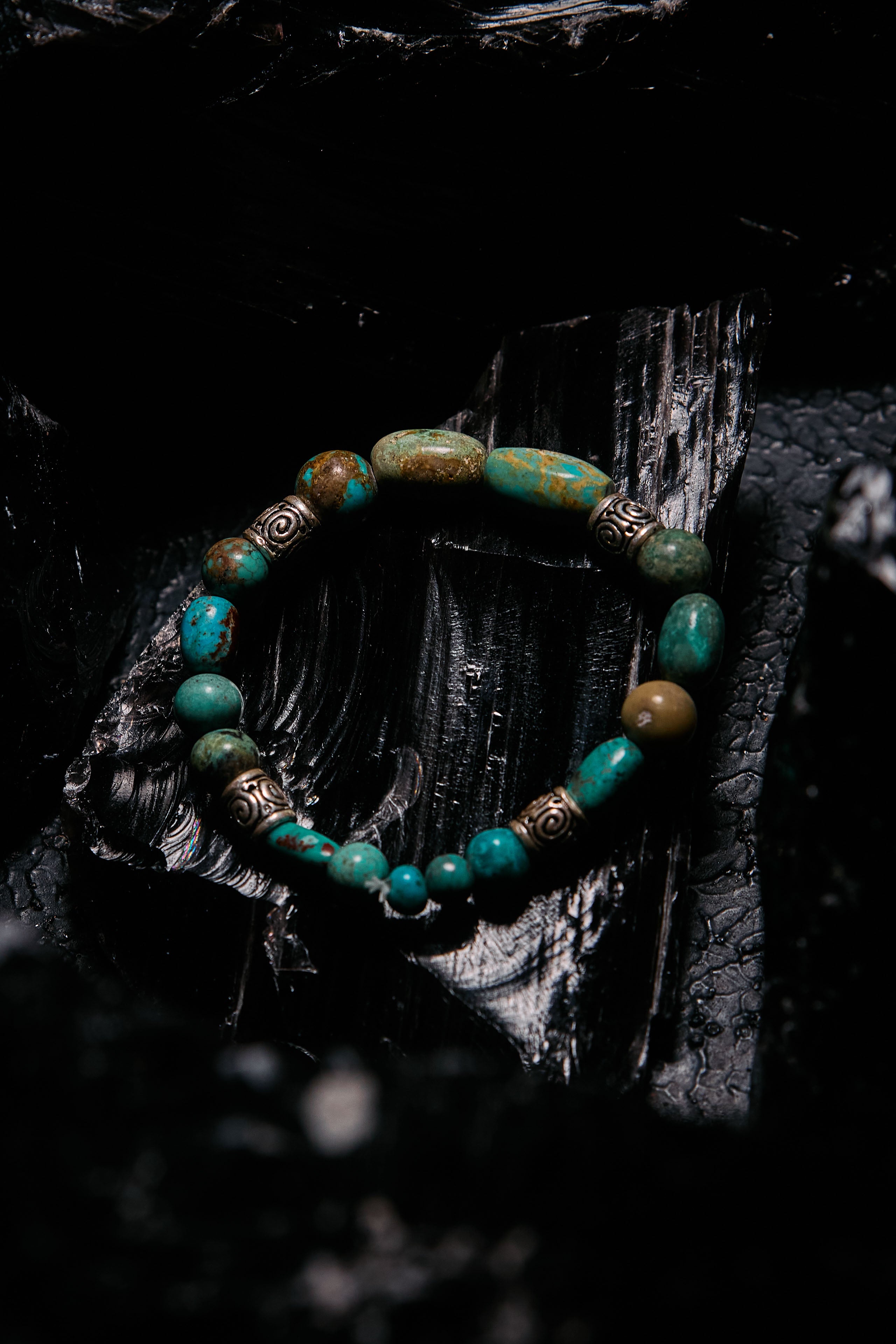 Turquoise beaded bracelet with gold accents on a dark textured surface