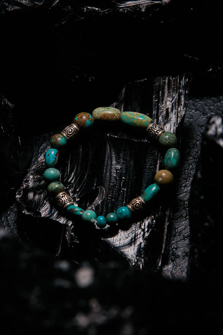 Turquoise beaded bracelet with gold accents on a dark textured surface