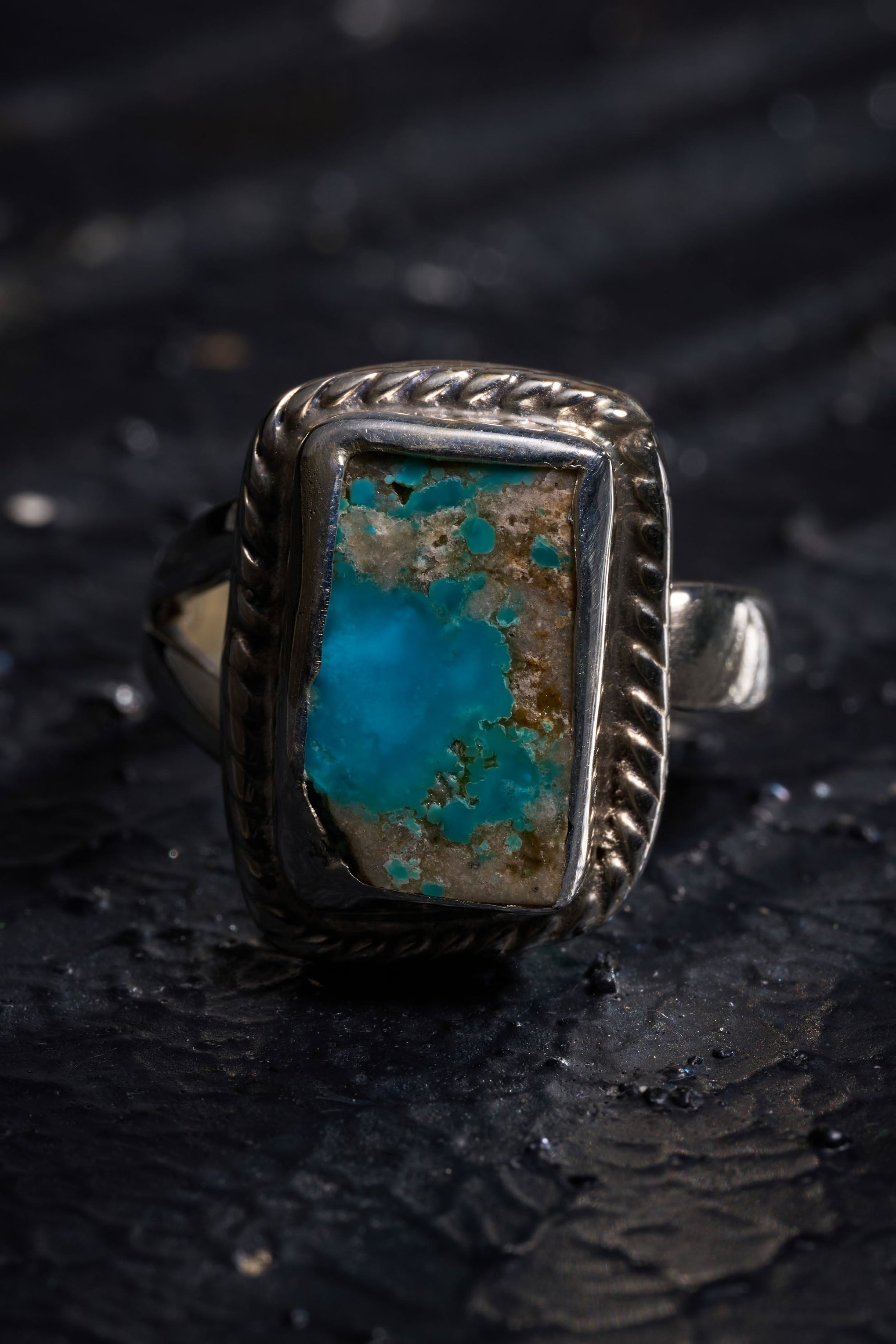 Silver ring with a turquoise stone on a dark textured surface