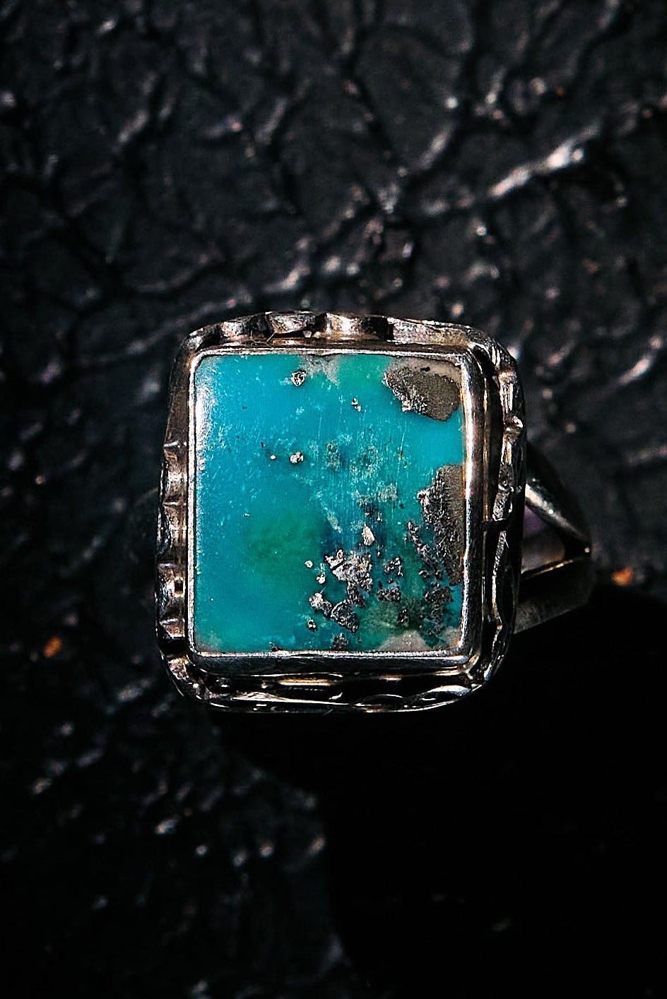Turquoise stone ring on a textured black background