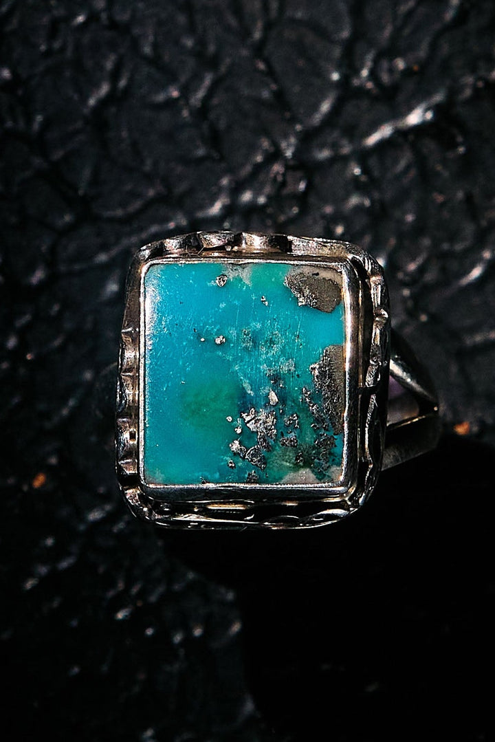 Turquoise stone ring on a textured black background