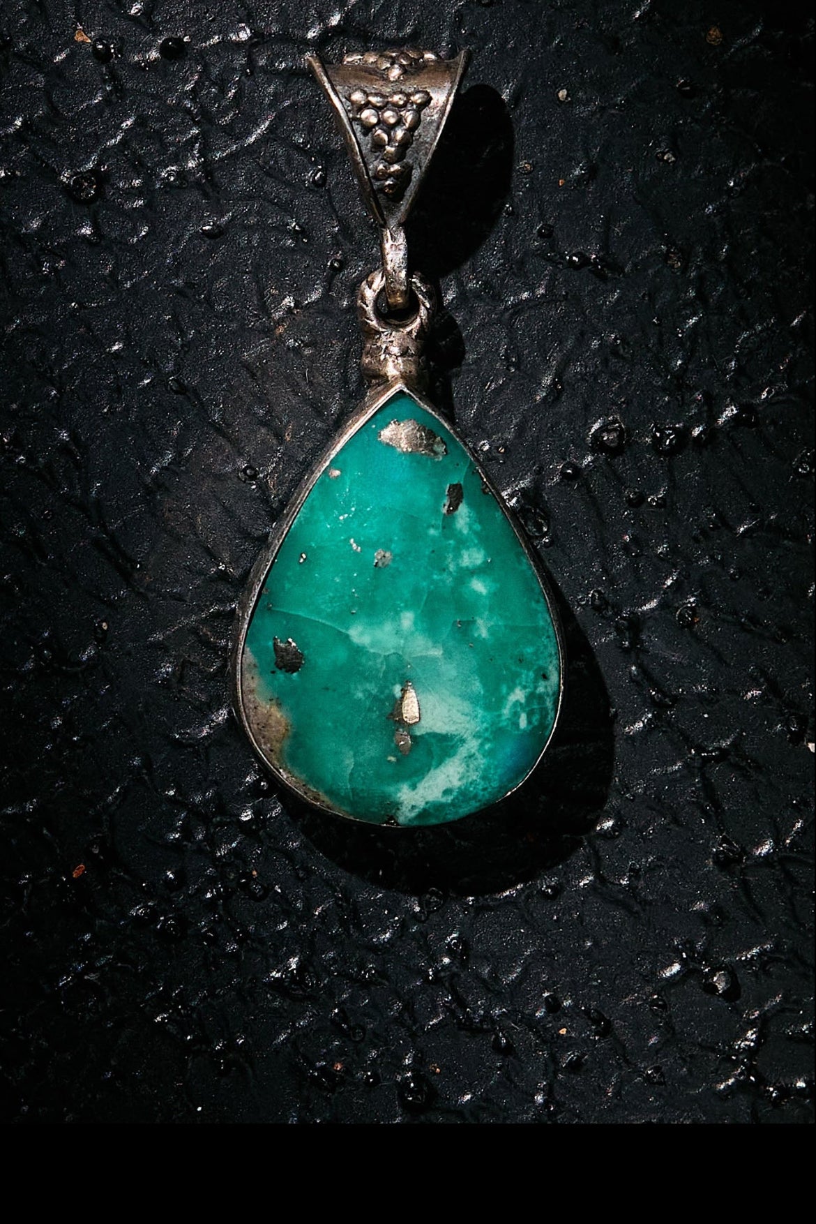 Turquoise pendant on 925 silver a dark textured background