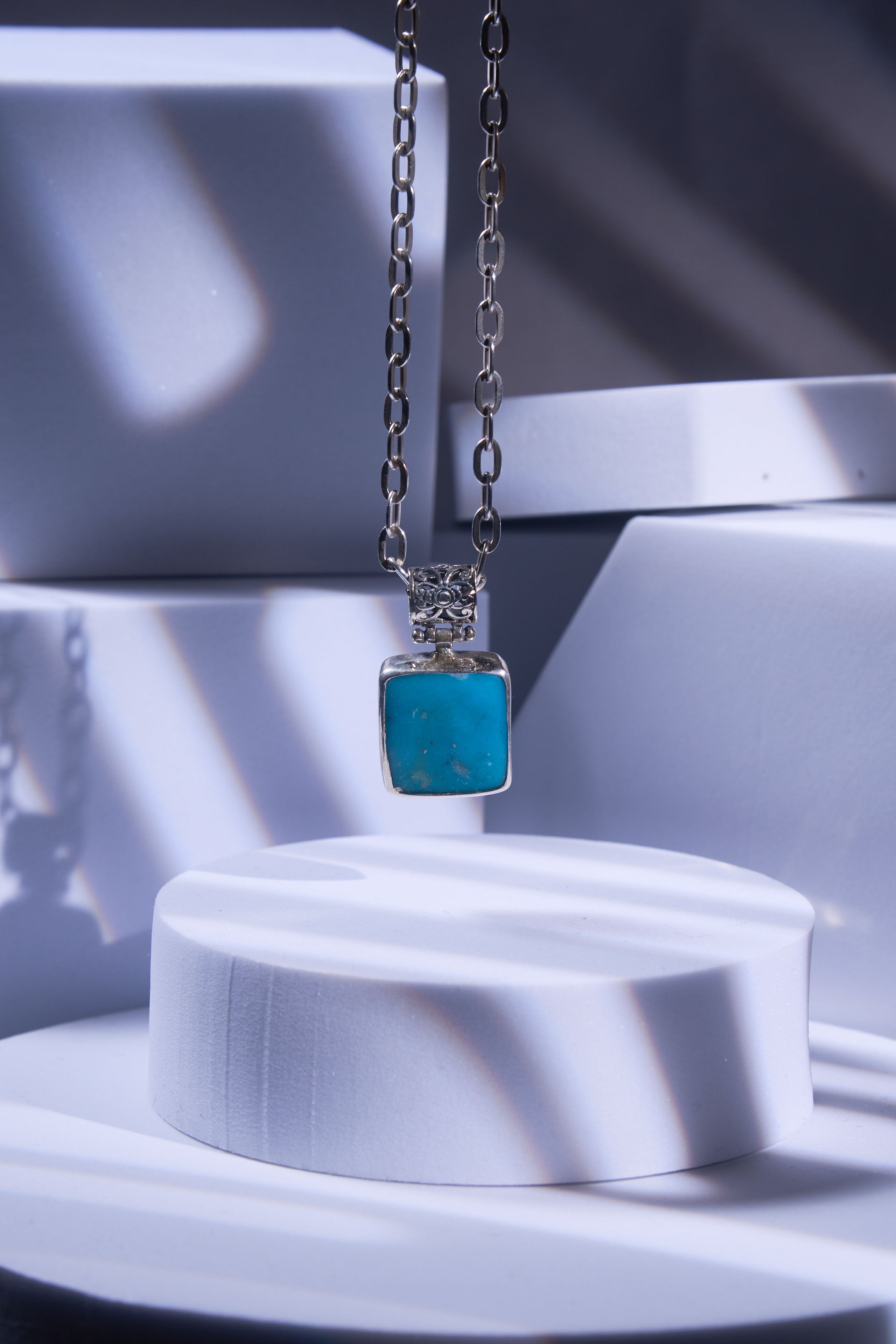 Necklace with a turquoise pendant on a white stand