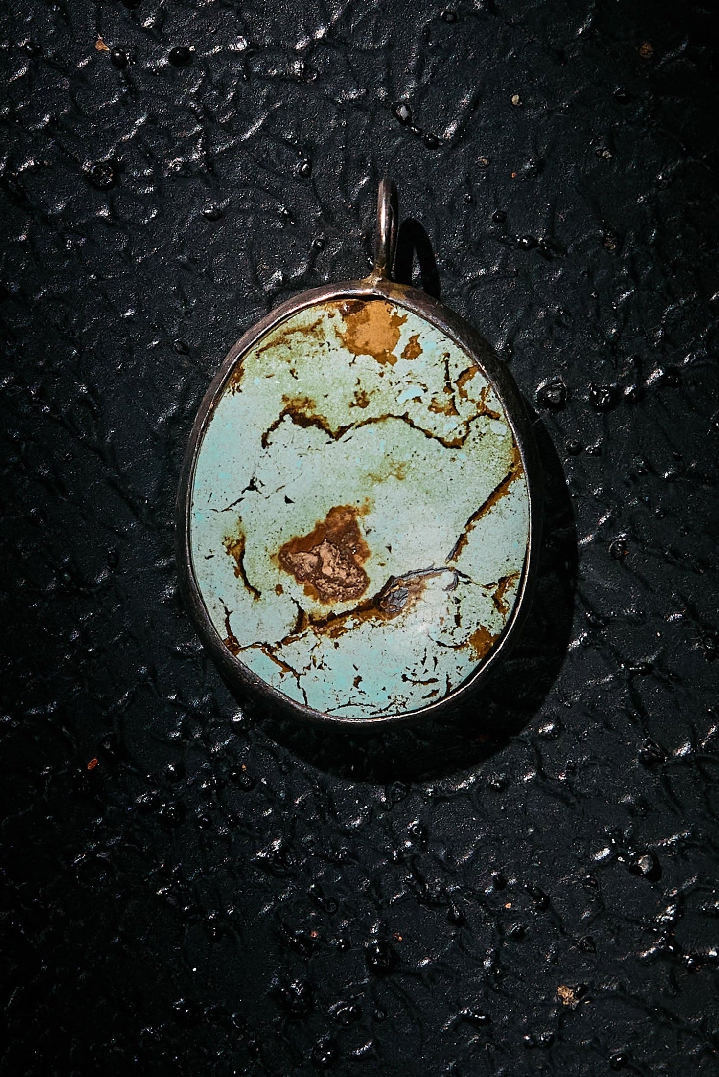 Turquoise stone pendant in 925 silver on a dark textured surface