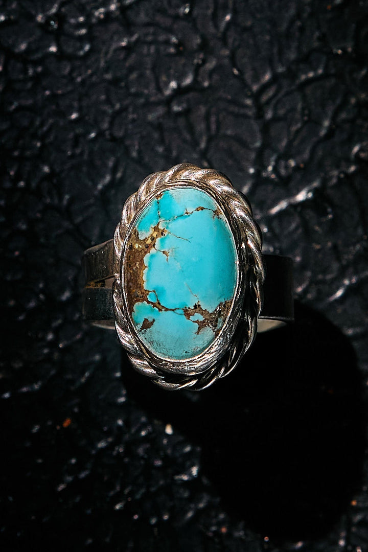 Turquoise ring with silver band on a textured black background