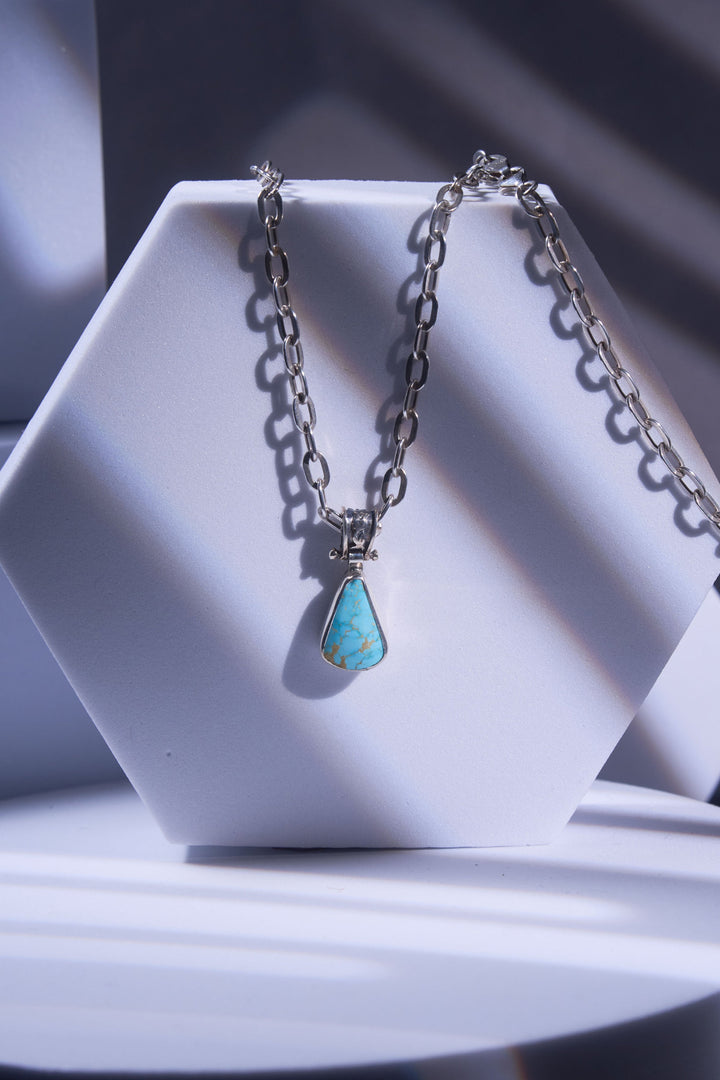 Necklace with a turquoise pendant on a white stand