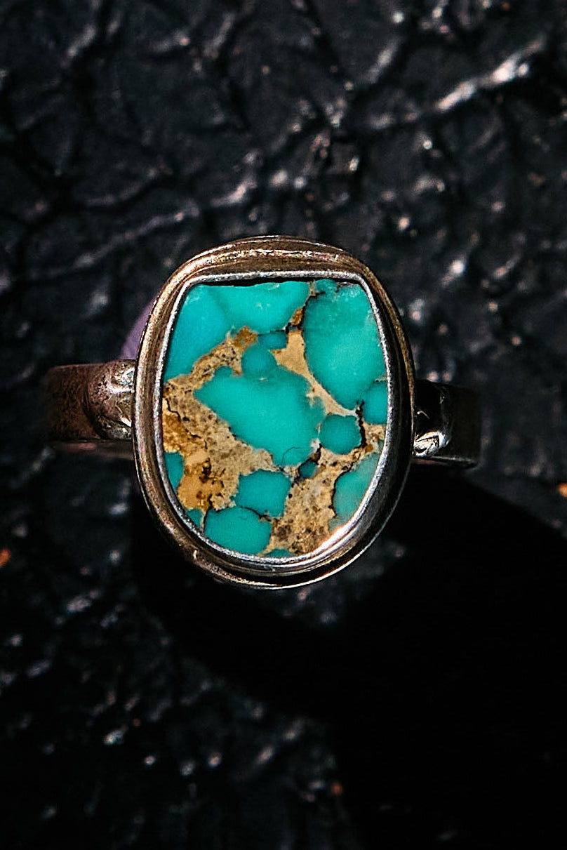 Turquoise ring with silver setting on a black textured background