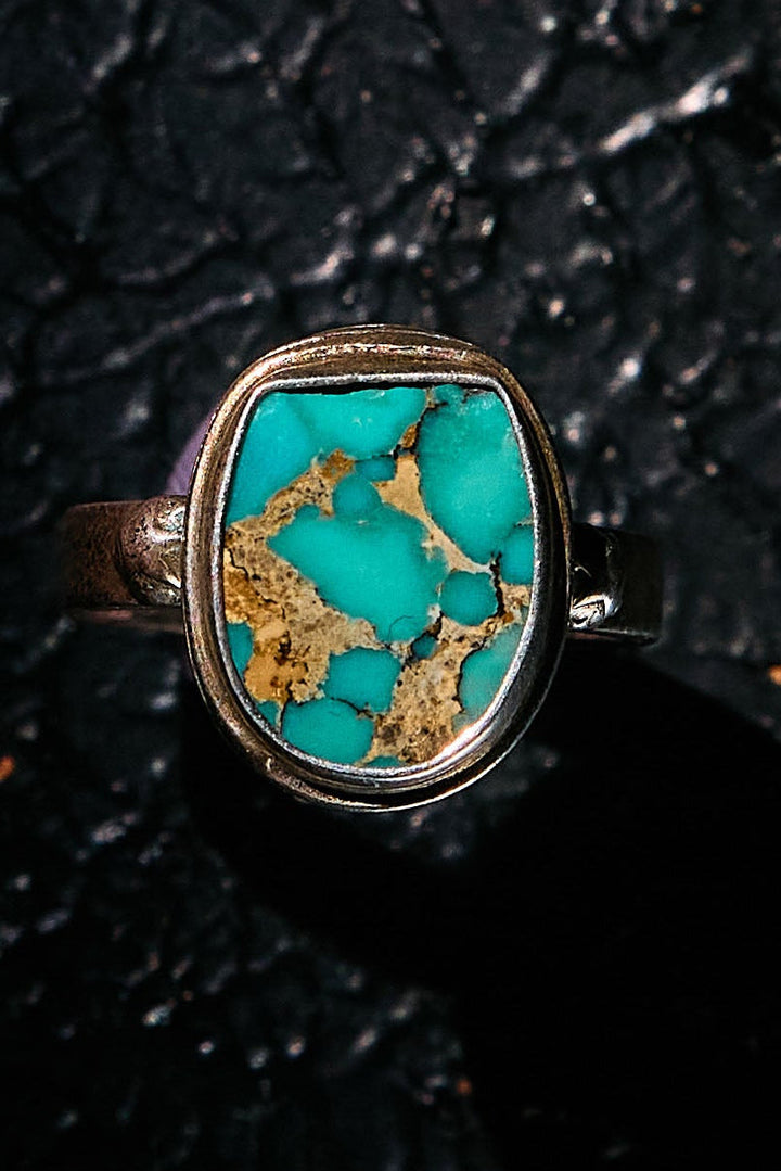 Turquoise ring with silver setting on a black textured background