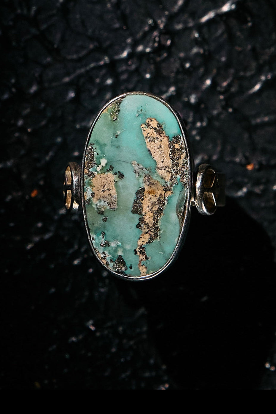 Turquoise ring with 925 silver setting on a textured black background