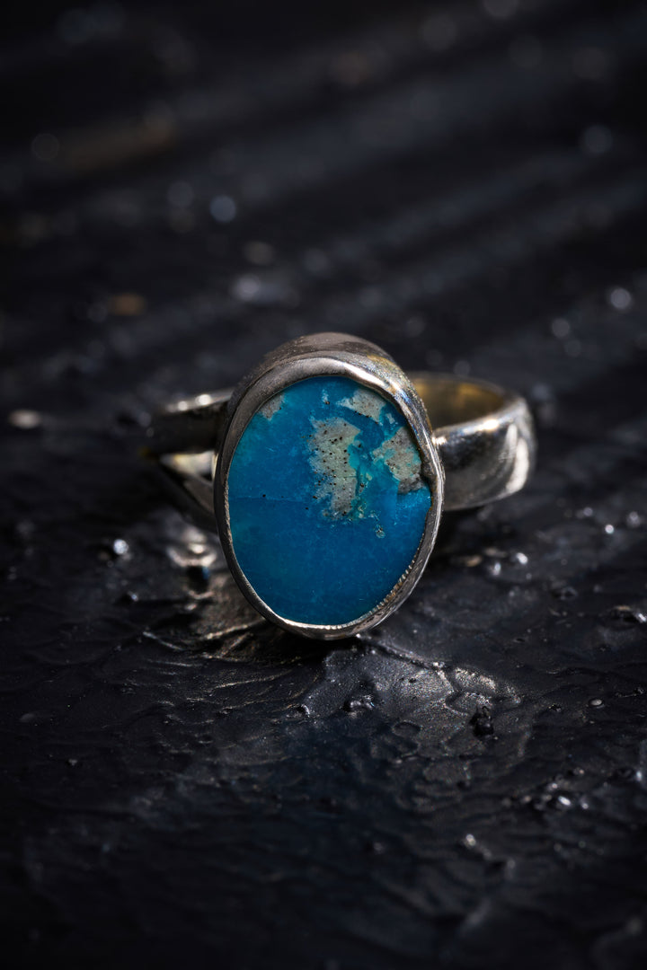 Silver ring with a turquoise stone on a dark textured surface