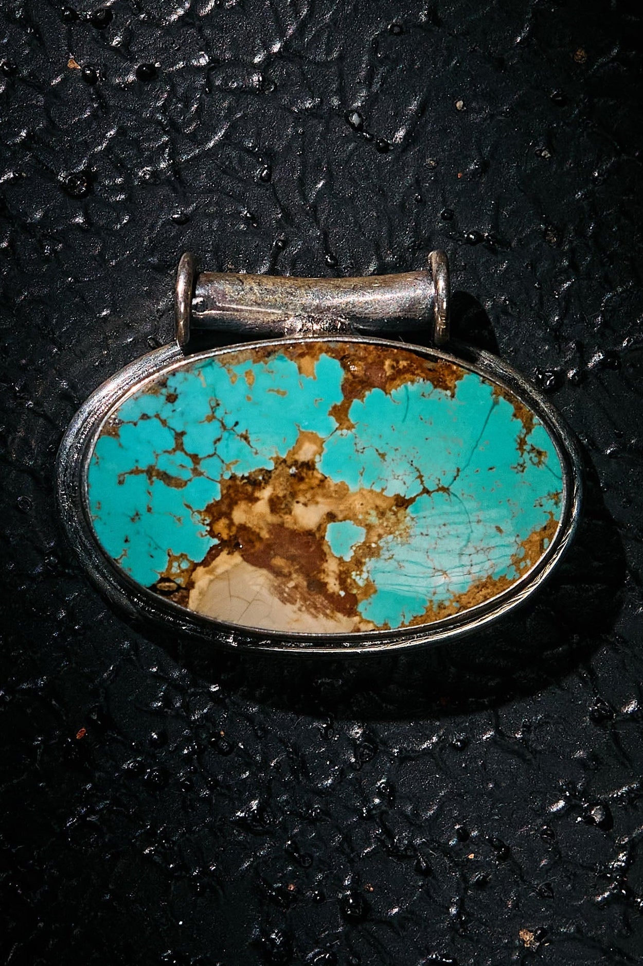 Turquoise stone pendant on a dark textured background