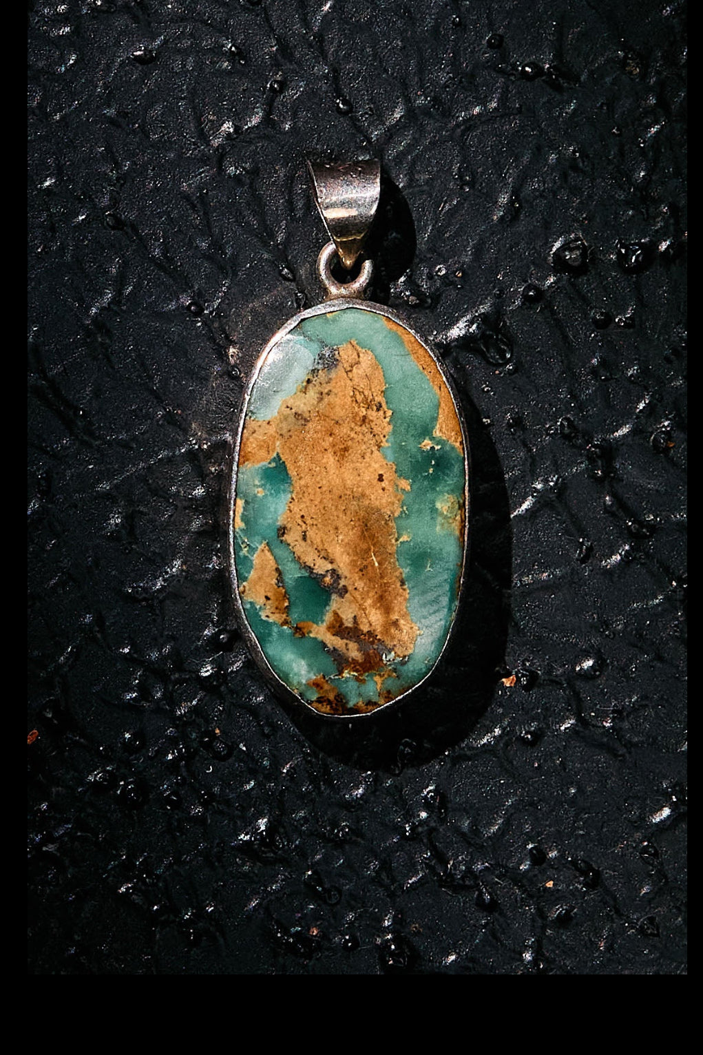 Turquoise pendant on 925 silver on a textured black background