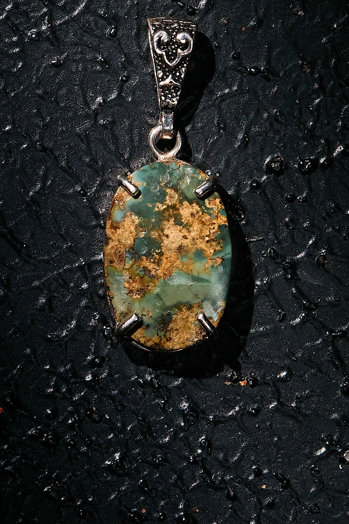 Pendant with a green stone on a dark textured surface