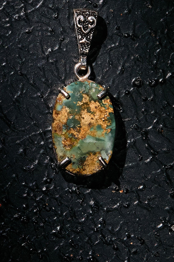 Pendant with a green stone on a dark textured surface