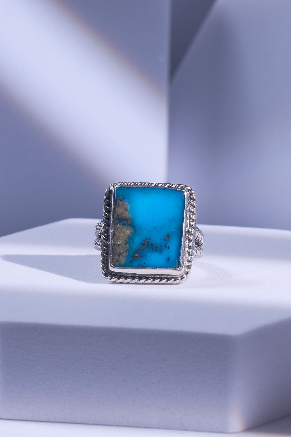 Turquoise ring with silver band on a light blue background, Silver sphinx guide strong here.
