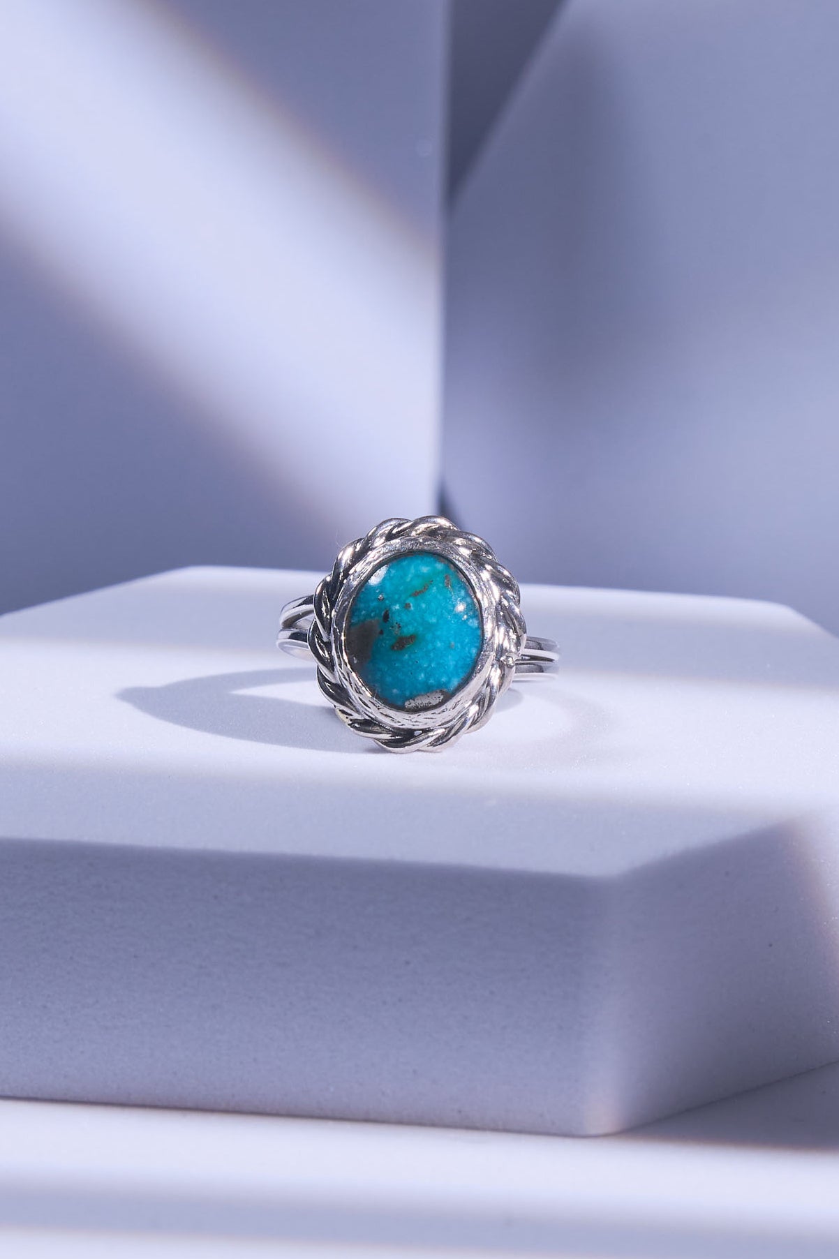 Silver ring with a turquoise stone on a light snowy blue background