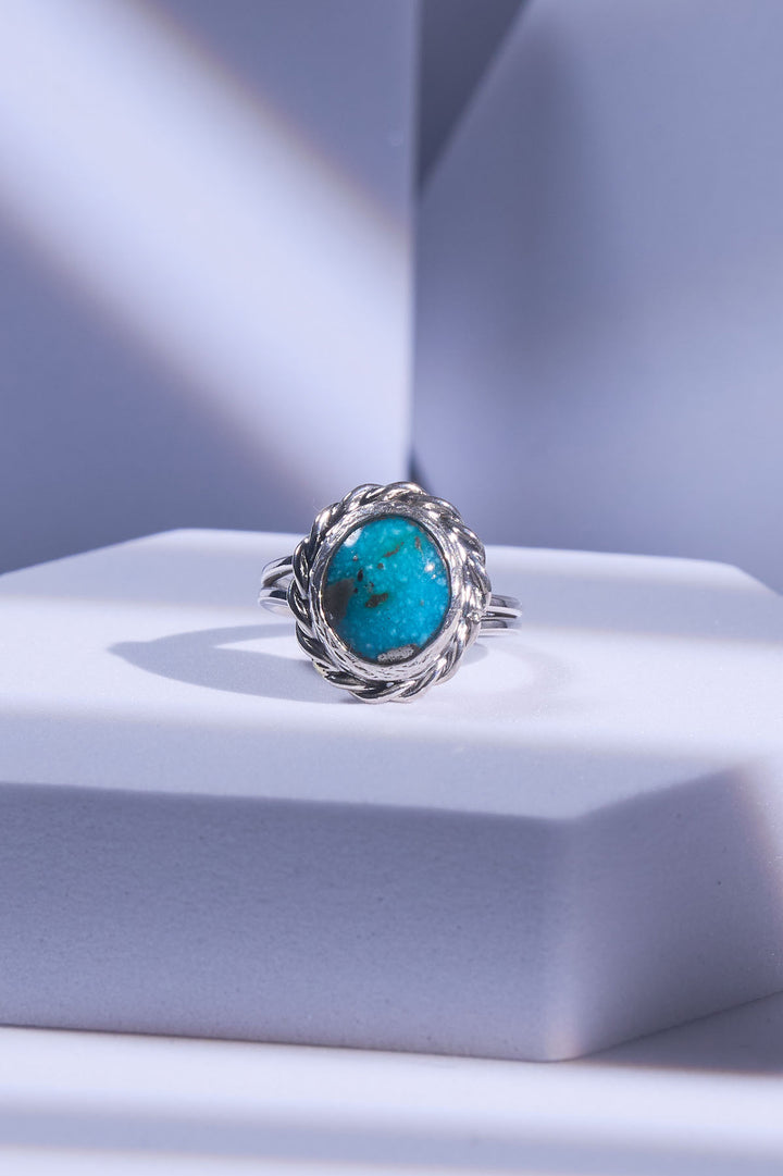 Silver ring with a turquoise stone on a light snowy blue background