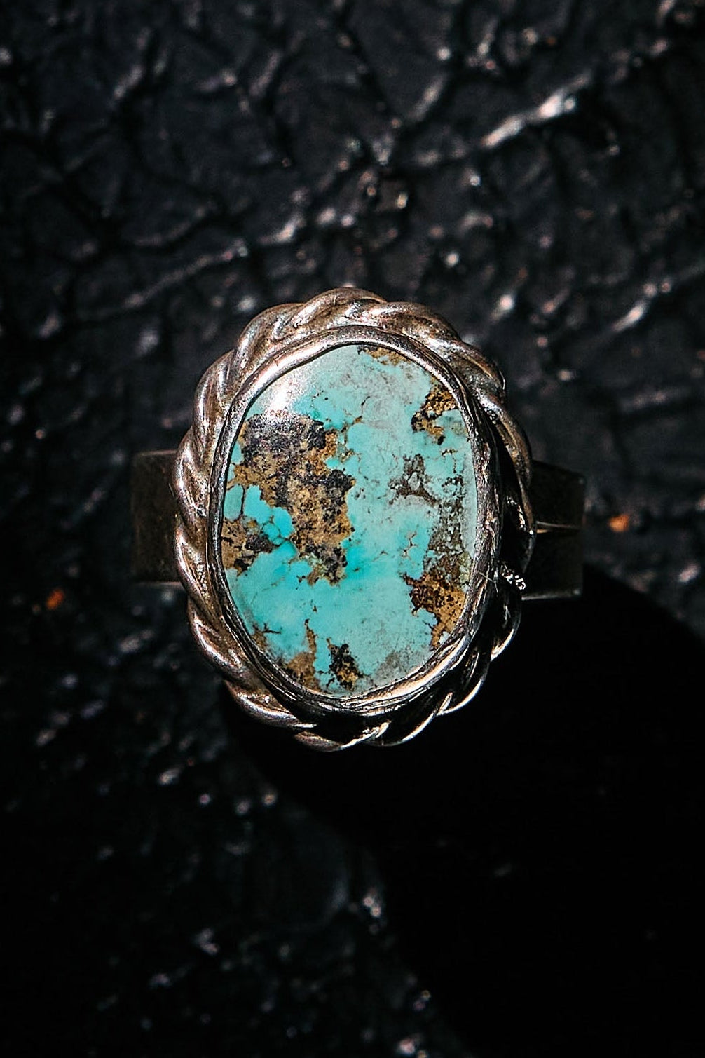 Turquoise ring with silver setting on a textured black surface