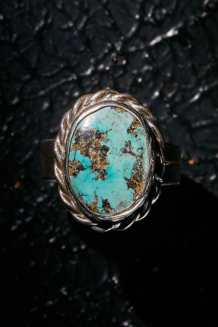 Turquoise ring with silver setting on a textured black surface