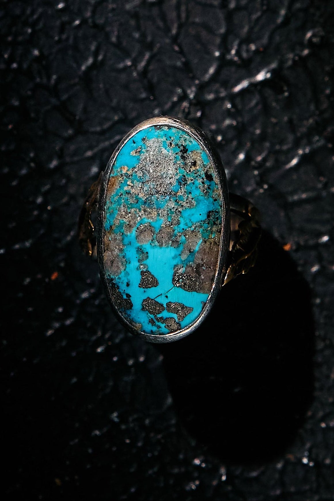 Turquoise ring with 925 silver band on a dark textured background