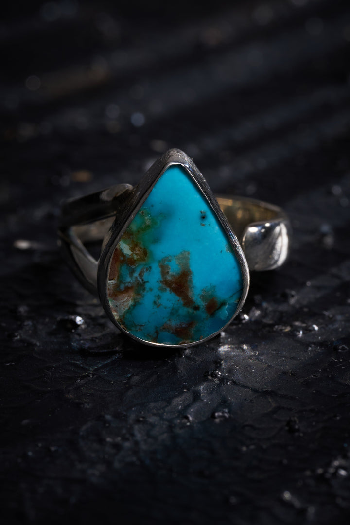 Silver ring with a large turquoise stone on a dark textured background