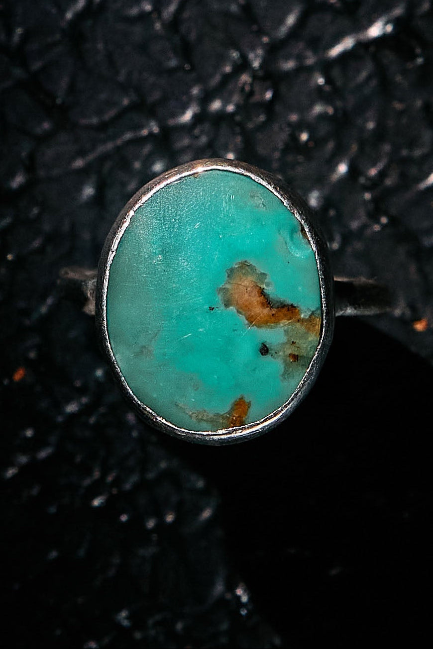 Turquoise ring with 925 silver setting on a textured black background