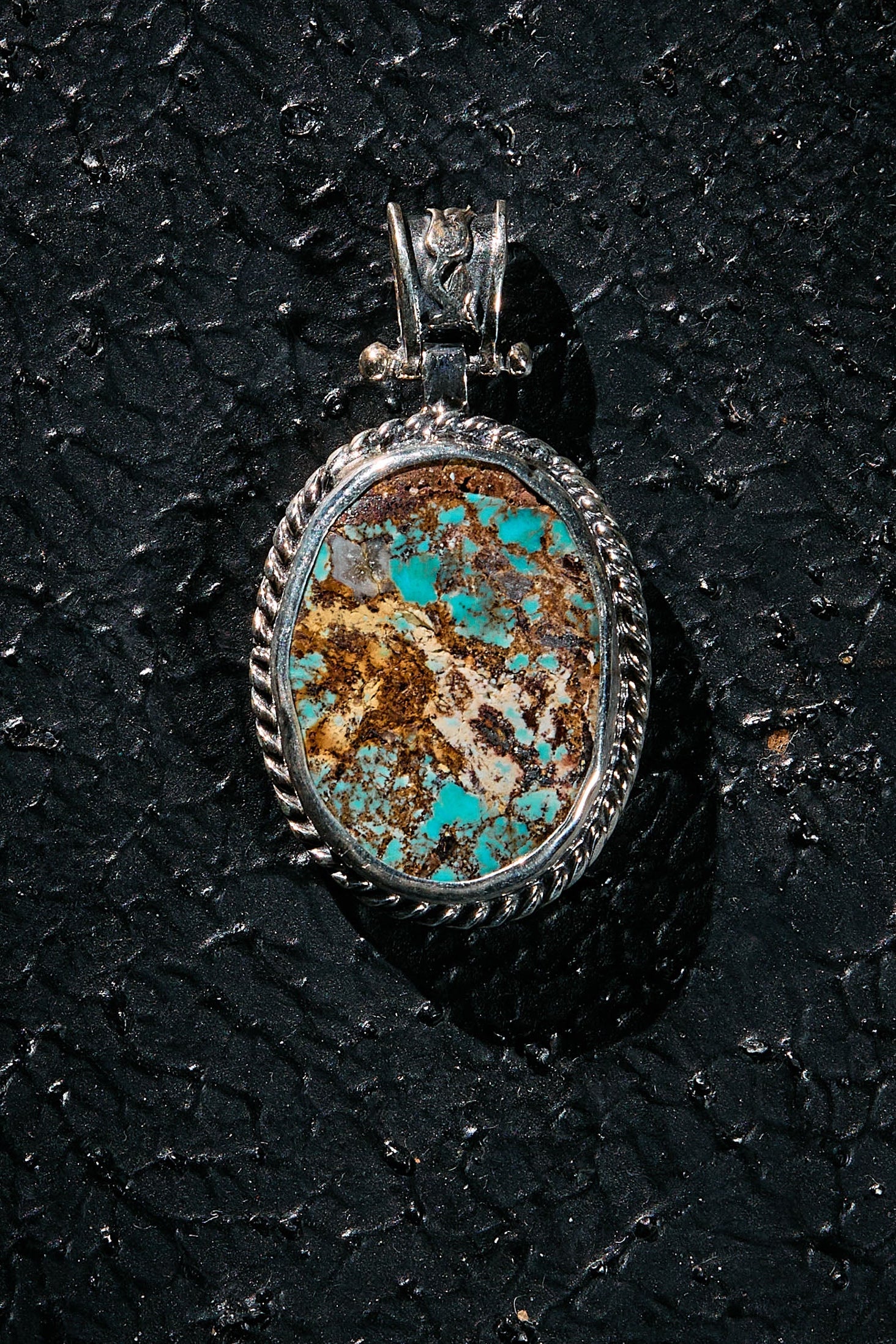 Turquoise stone pendant on a dark textured surface