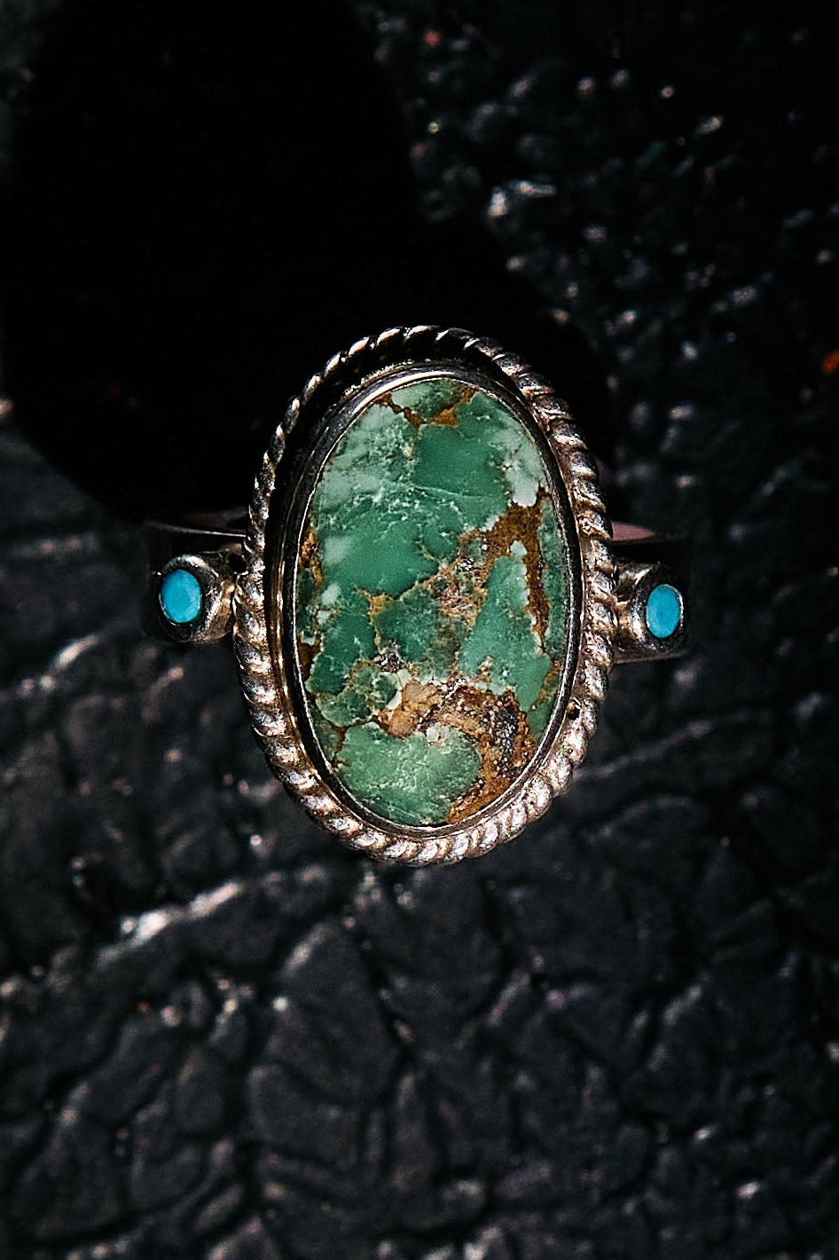 Turquoise ring with silver setting on a textured black surface