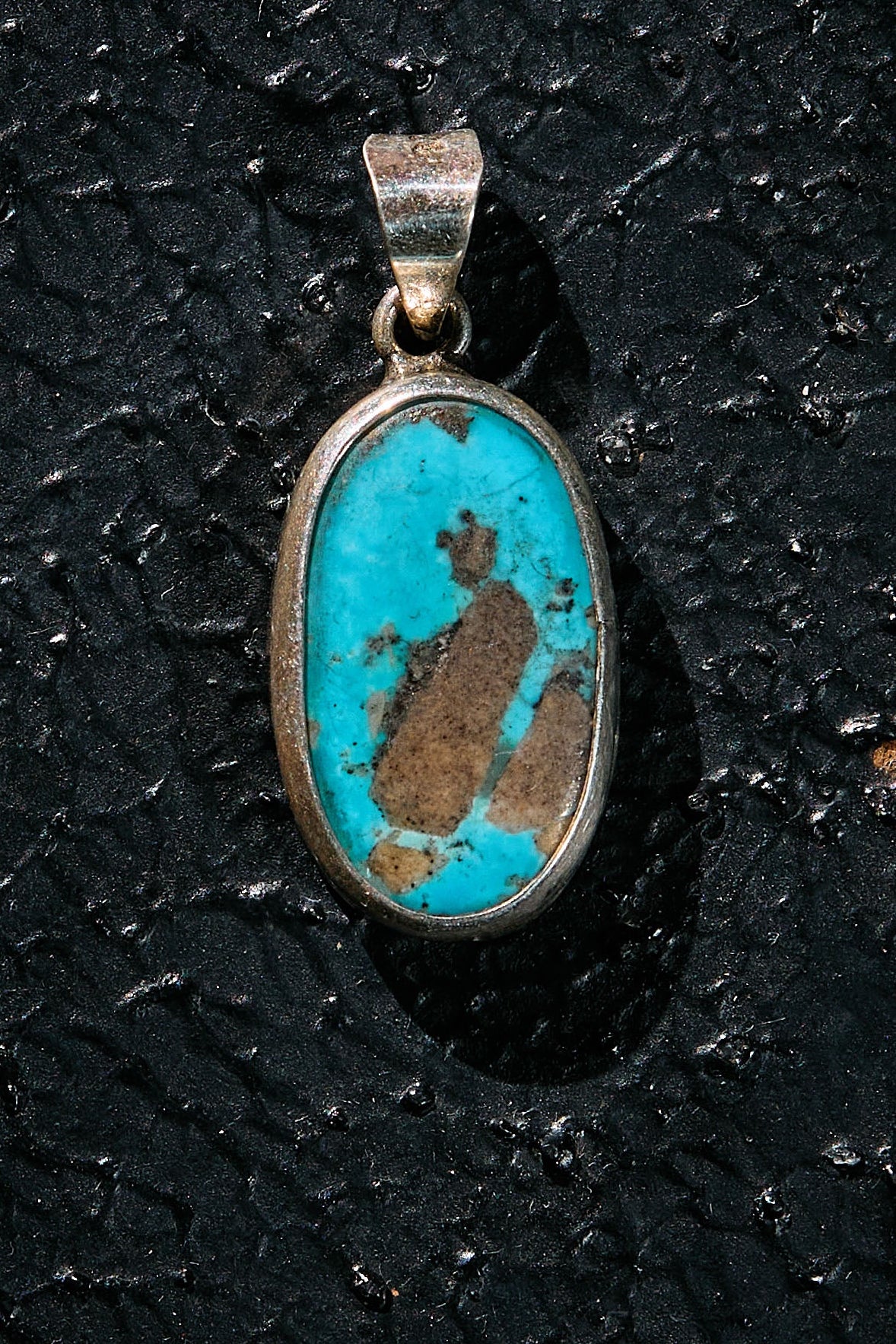 Turquoise stone pendant on a black textured background
