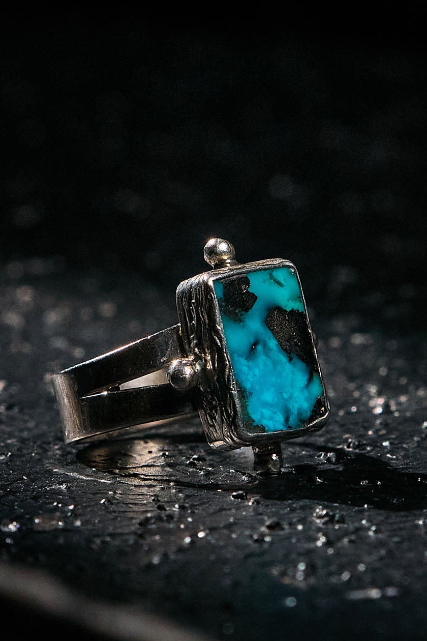Silver ring with a turquoise stone on a dark surface
