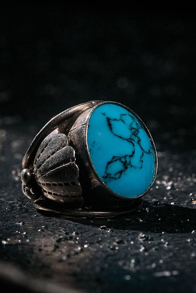 Silver ring with a turquoise stone on a dark surface