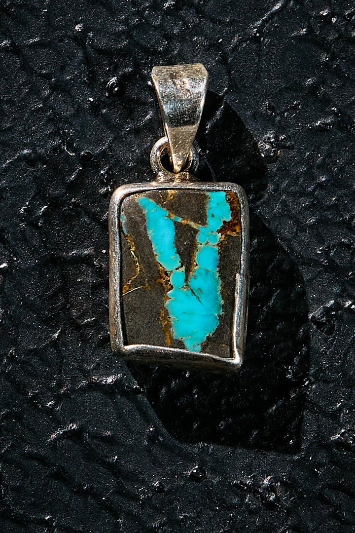Turquoise stone pendant in a silver frame with a natural V